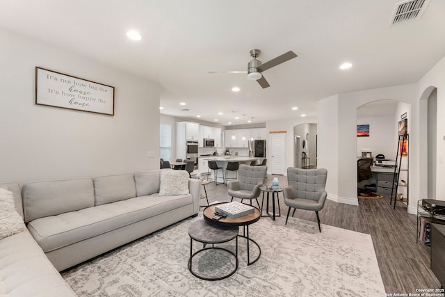 living area with ceiling fan, dark wood finished floors, arched walkways, visible vents, and recessed lighting