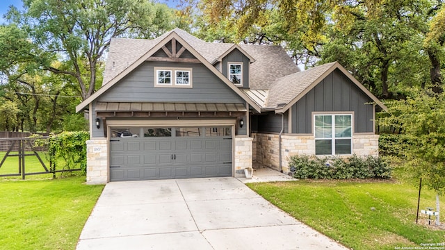 craftsman-style house featuring board and batten siding, a front yard, stone siding, fence, and driveway