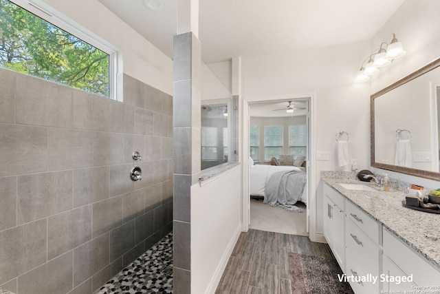 ensuite bathroom featuring ceiling fan, a walk in shower, ensuite bath, wood finished floors, and vanity
