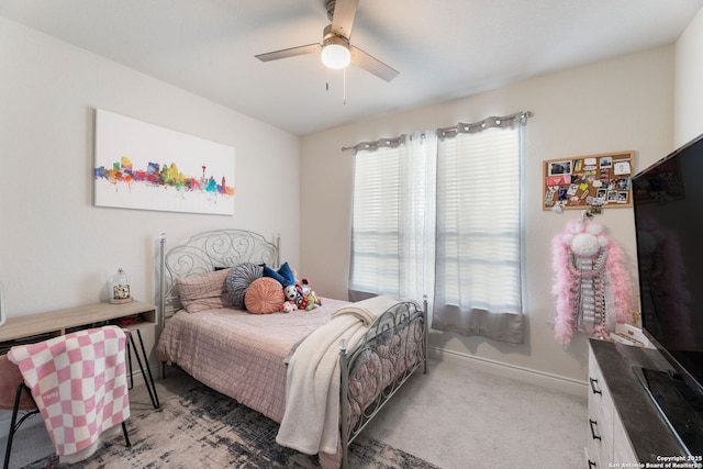 bedroom featuring light colored carpet, multiple windows, baseboards, and ceiling fan