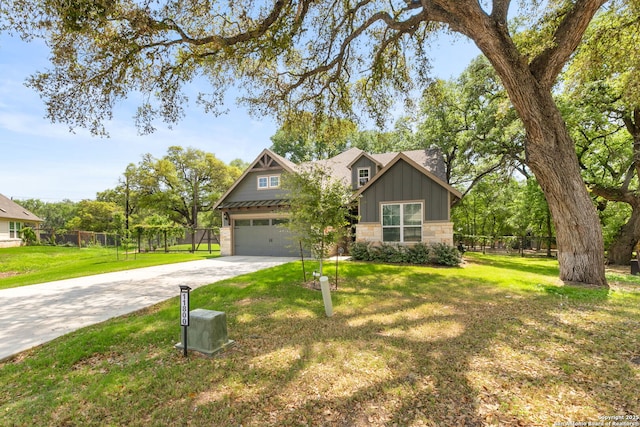 craftsman-style home with concrete driveway, stone siding, fence, and a front lawn