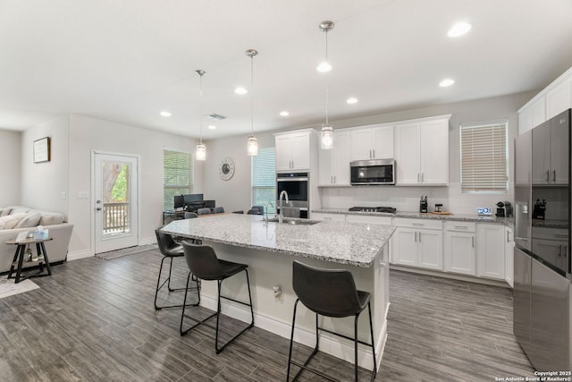 kitchen with tasteful backsplash, open floor plan, a kitchen bar, appliances with stainless steel finishes, and a sink