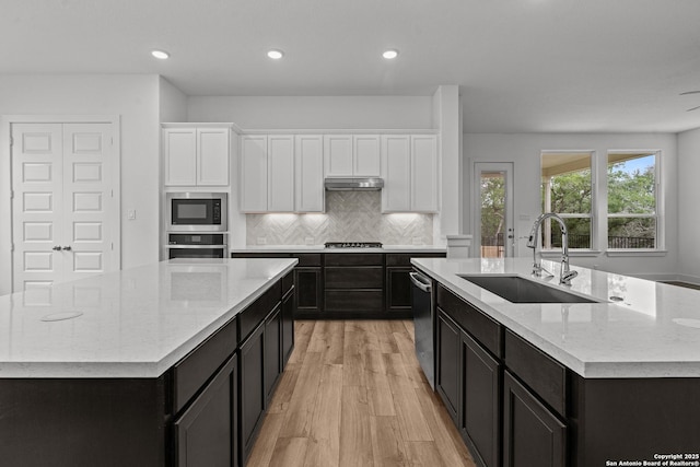 kitchen featuring a sink, a spacious island, light wood finished floors, white cabinets, and appliances with stainless steel finishes