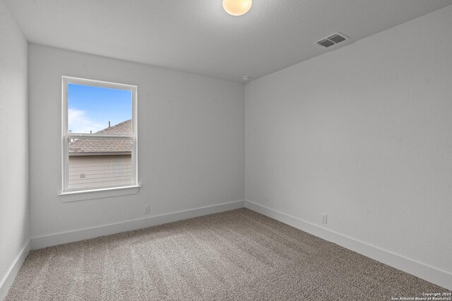 carpeted spare room featuring visible vents and baseboards