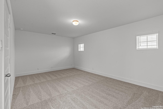 carpeted empty room featuring baseboards and visible vents