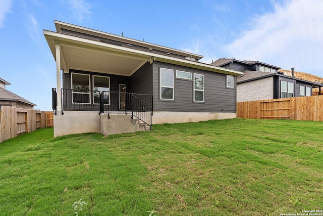 rear view of property featuring a fenced backyard and a lawn