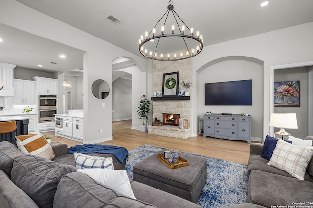 1064 Spanish Trl, New Braunfels, TX 78132 - living room featuring visible vents, light wood-style flooring, arched walkways, and an inviting chandelier