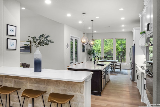 1064 Spanish Trl, New Braunfels, TX 78132 - kitchen with light countertops, light wood-style floors, a center island with sink, stainless steel appliances, and a sink