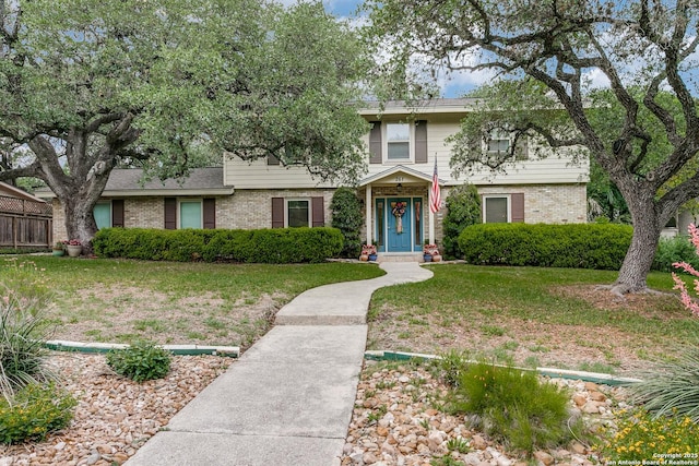 traditional home featuring fence, a front lawn, and brick siding