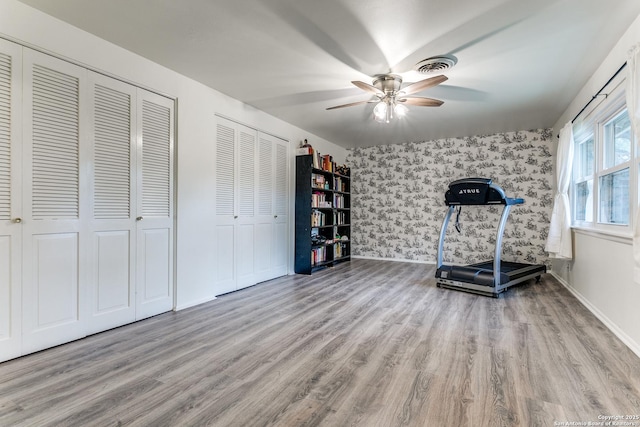 workout room with wallpapered walls, a ceiling fan, wood finished floors, and baseboards