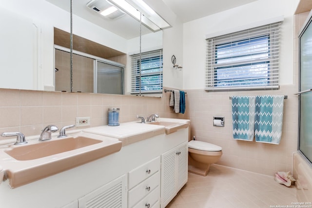 full bath featuring tile walls, plenty of natural light, a sink, and a shower with shower door