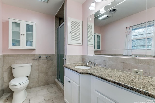 full bathroom featuring tile patterned floors, toilet, tile walls, a stall shower, and vanity