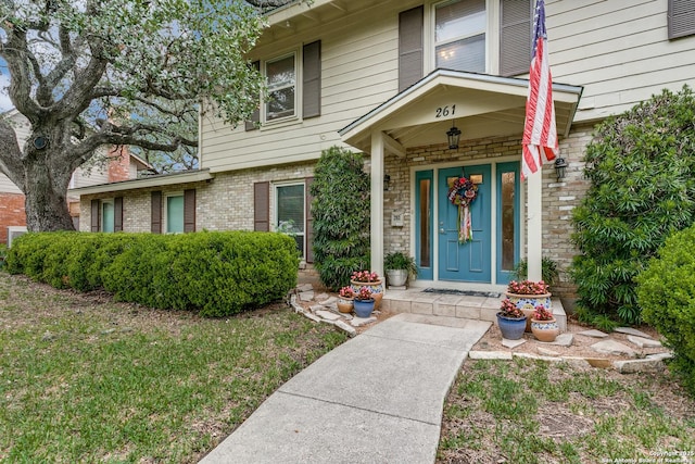 doorway to property featuring brick siding and covered porch
