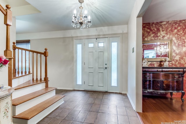 foyer entrance featuring stairs, baseboards, and a chandelier