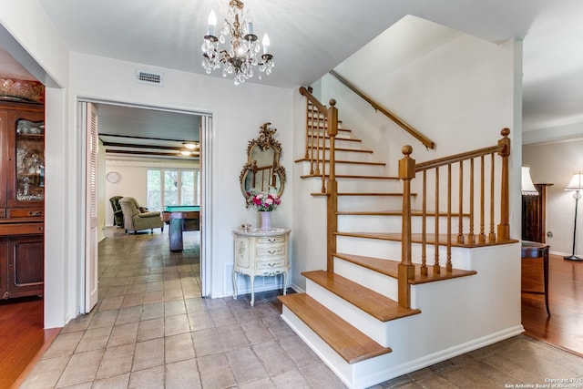 stairs featuring visible vents, baseboards, and a notable chandelier