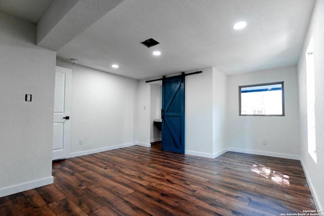 basement featuring baseboards, recessed lighting, a barn door, and wood finished floors