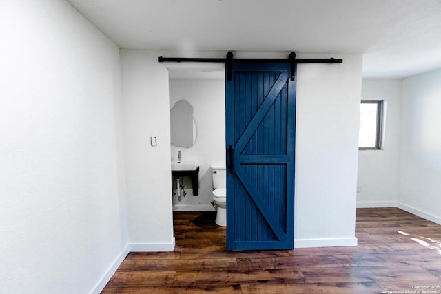 interior space with wood finished floors, baseboards, and a barn door