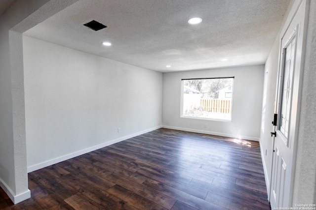 spare room with dark wood finished floors, recessed lighting, baseboards, and a textured ceiling