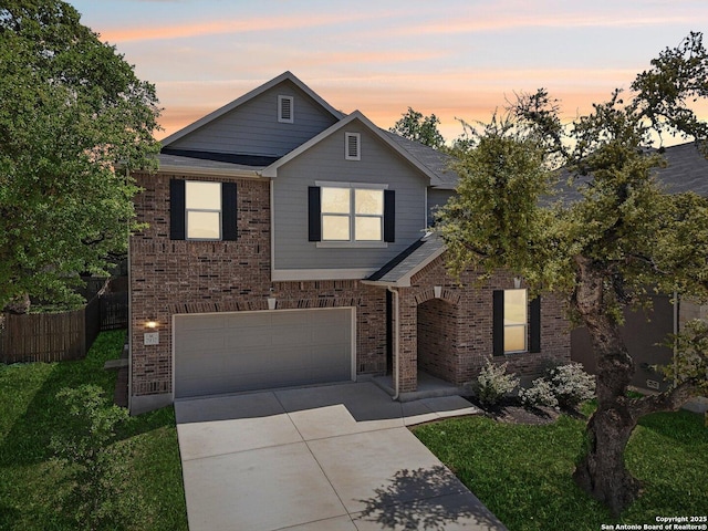 traditional-style house featuring an attached garage, concrete driveway, fence, and brick siding