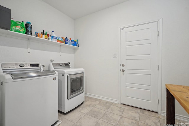 clothes washing area with washer and clothes dryer, light tile patterned flooring, laundry area, and baseboards