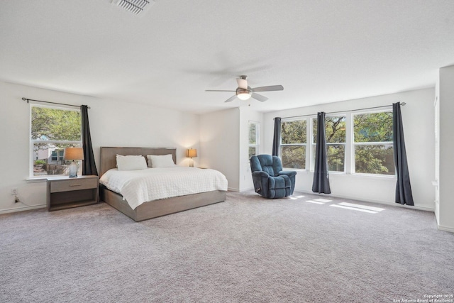 carpeted bedroom with baseboards, a ceiling fan, and visible vents