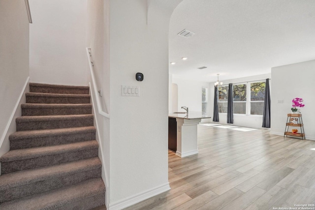 staircase with baseboards, recessed lighting, visible vents, arched walkways, and wood finished floors