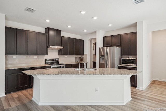 kitchen featuring visible vents, a sink, under cabinet range hood, dark brown cabinets, and stainless steel appliances