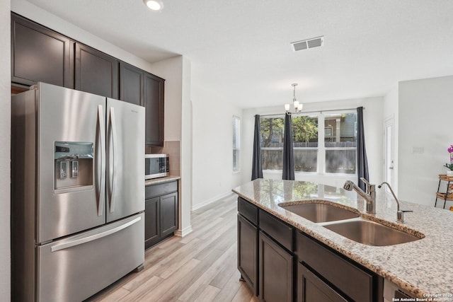kitchen featuring a chandelier, visible vents, stainless steel appliances, light wood finished floors, and a sink