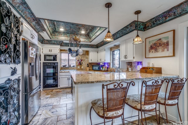 527 Thelma Dr, Olmos Park, TX 78212 - kitchen with white cabinets, a peninsula, black appliances, stone tile floors, and light stone counters