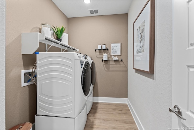 laundry room with visible vents, baseboards, washer and dryer, laundry area, and light wood finished floors