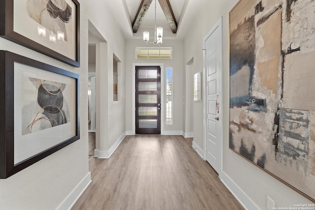 entryway featuring baseboards, an inviting chandelier, and wood finished floors