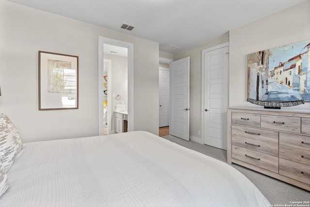 bedroom featuring visible vents, baseboards, carpet flooring, and ensuite bath