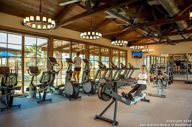 gym with high vaulted ceiling, ceiling fan with notable chandelier, and wood ceiling