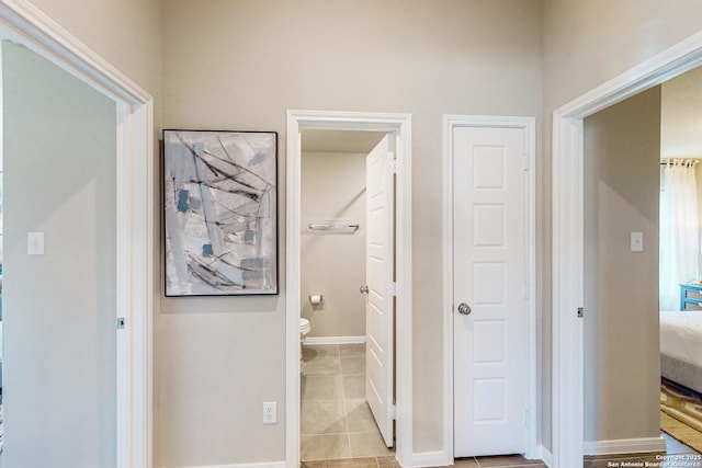 interior space featuring ensuite bath, toilet, tile patterned flooring, and baseboards