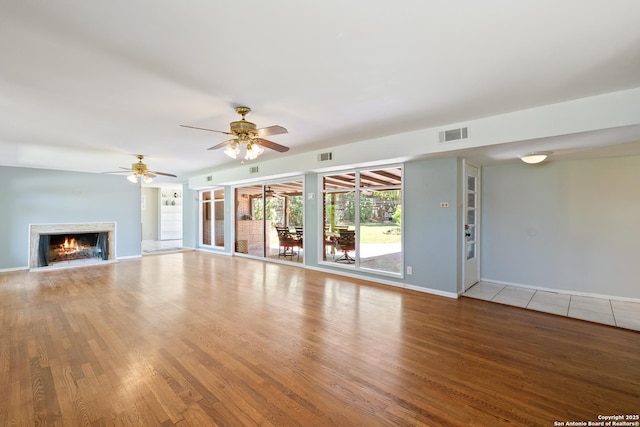 800 Eventide, Terrell Hills, TX 78209 - unfurnished living room with visible vents, baseboards, wood finished floors, and a lit fireplace