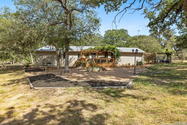 296 Wolf Ln, La Vernia, TX 78121 - exterior space with a standing seam roof, metal roof, a wooden deck, and a front lawn