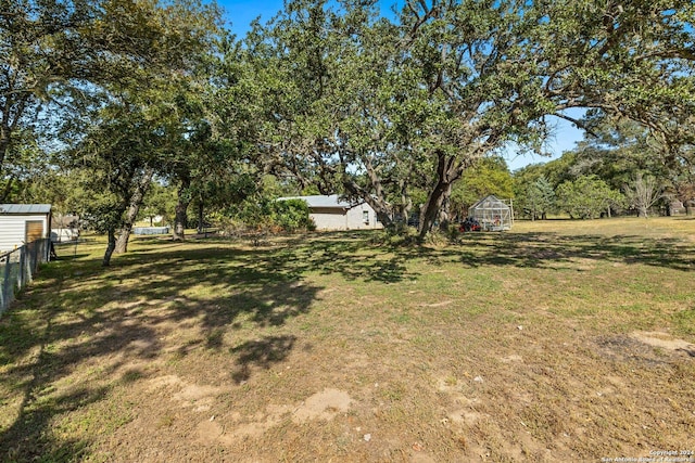 296 Wolf Ln, La Vernia, TX 78121 - view of yard with a greenhouse, an outbuilding, and fence