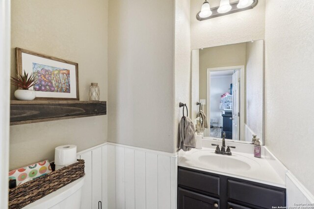 bathroom featuring vanity, wainscoting, and toilet