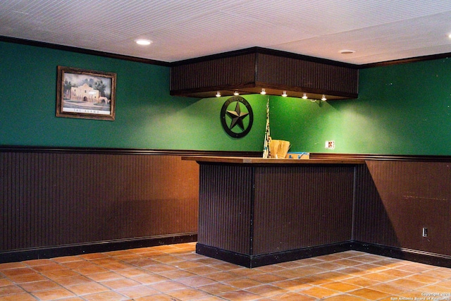 bar with tile patterned flooring, wainscoting, ornamental molding, and indoor bar