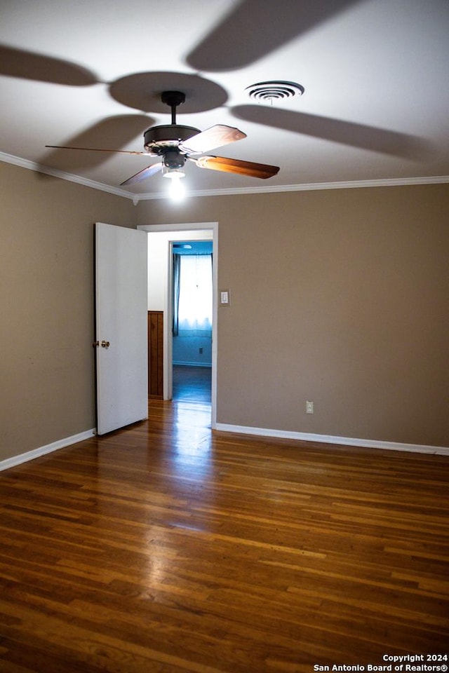 spare room featuring crown molding, visible vents, baseboards, and wood finished floors