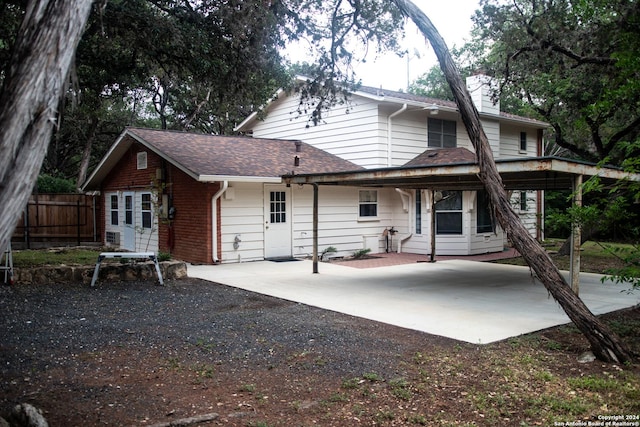 back of property with brick siding, a chimney, fence, and gravel driveway