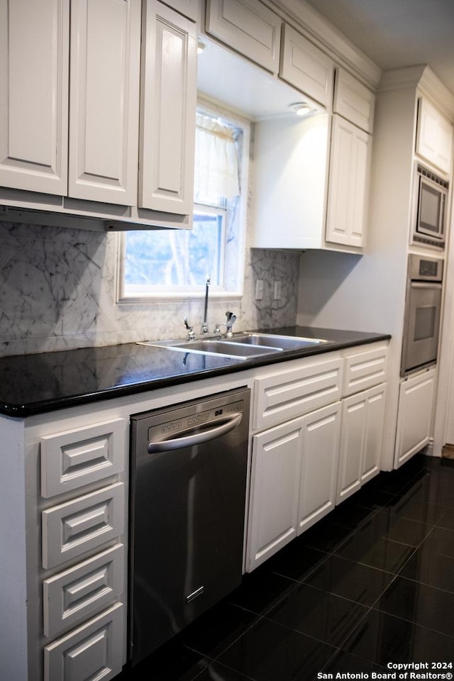 kitchen featuring stainless steel appliances, white cabinets, a sink, and dark countertops