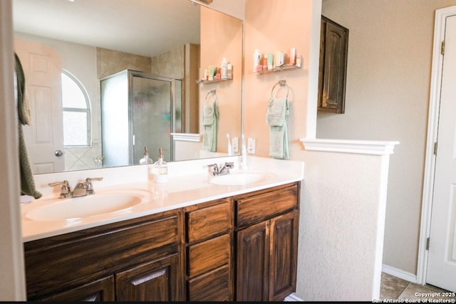 bathroom with tile patterned floors, double vanity, a sink, and a stall shower