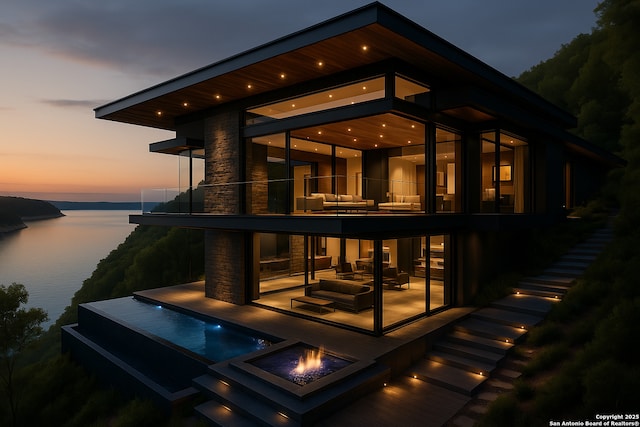 back of property featuring an outdoor fire pit, a balcony, a patio area, and a water view