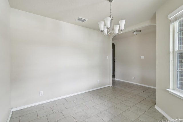 empty room featuring baseboards, arched walkways, visible vents, and a wealth of natural light