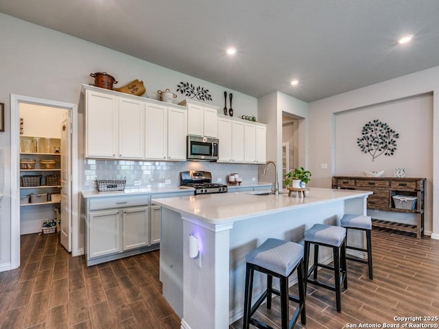 kitchen featuring tasteful backsplash, a breakfast bar, dark wood-style floors, appliances with stainless steel finishes, and a sink