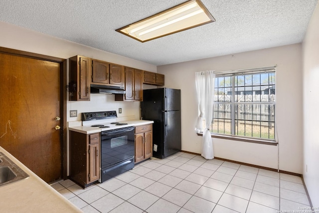 kitchen featuring light countertops, freestanding refrigerator, a textured ceiling, under cabinet range hood, and electric range oven
