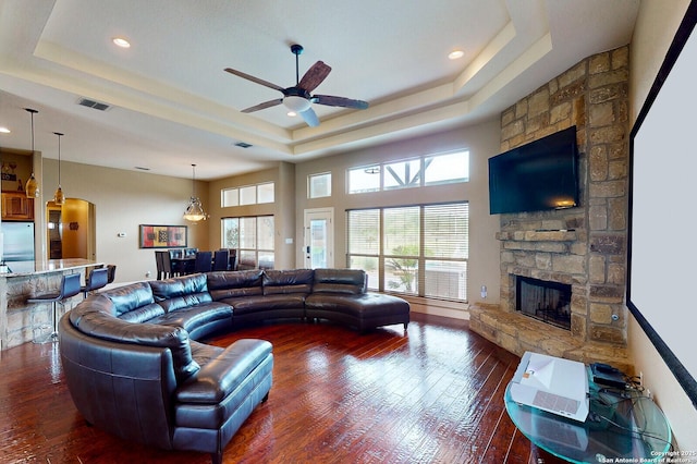 224 E Copper Trce, New Braunfels, TX 78132 - living area featuring a tray ceiling, dark wood finished floors, a stone fireplace, and visible vents