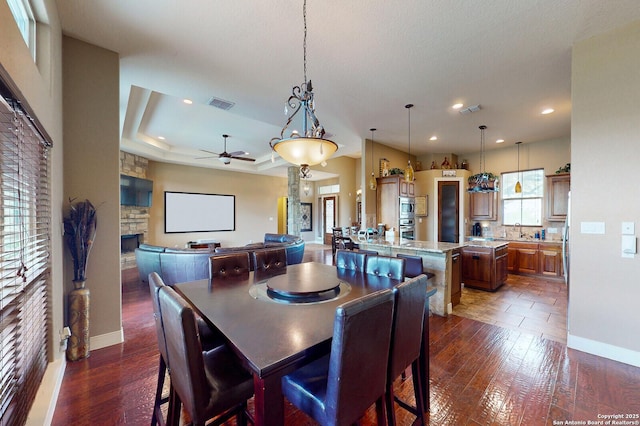224 E Copper Trce, New Braunfels, TX 78132 - dining room featuring a fireplace, dark wood finished floors, a ceiling fan, visible vents, and baseboards