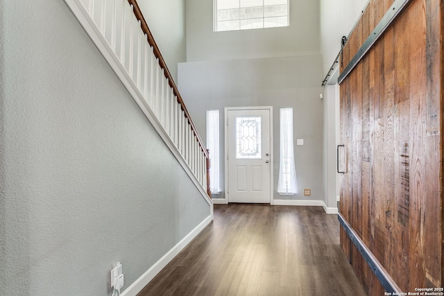 foyer entrance featuring a high ceiling, plenty of natural light, a barn door, and wood finished floors
